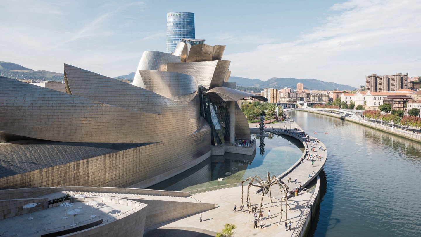 Bilbao, Spain - October 06, 2016. People strolls along the riverside promenade at the Nervi&oacute;n river that runs through the city into the Cantabrian Sea. On the left side, the world famous Guggenheim Museum. It is the main attraction in Bilbao