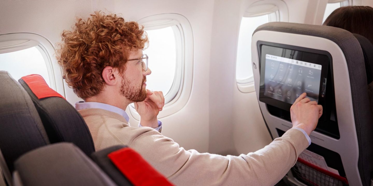 Passagier der Premium Economy Class bedient den Bildschirm an seinem Platz