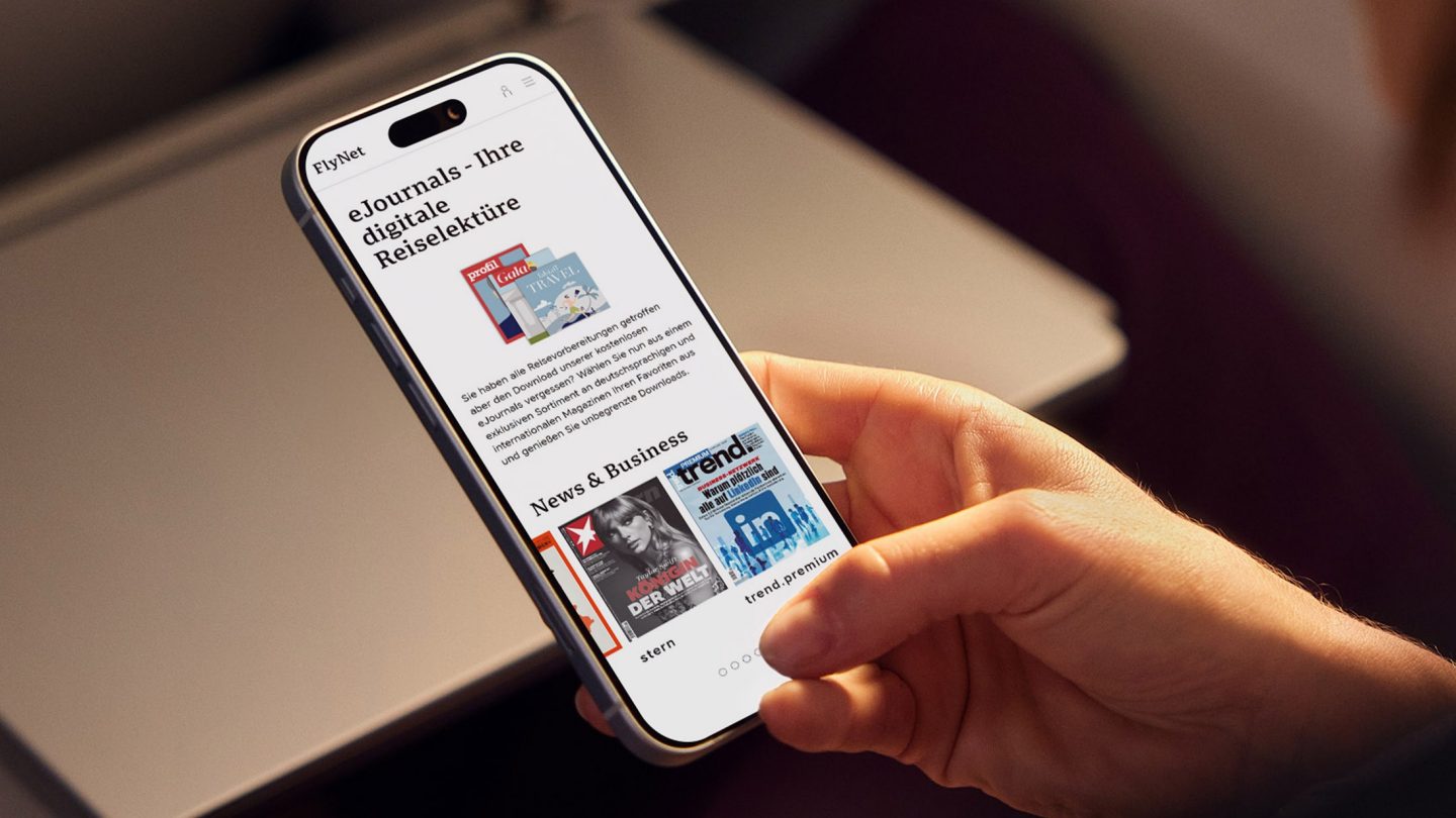 A smartphone in one hand displaying the digital selection of eJournals in the FlyNet portal