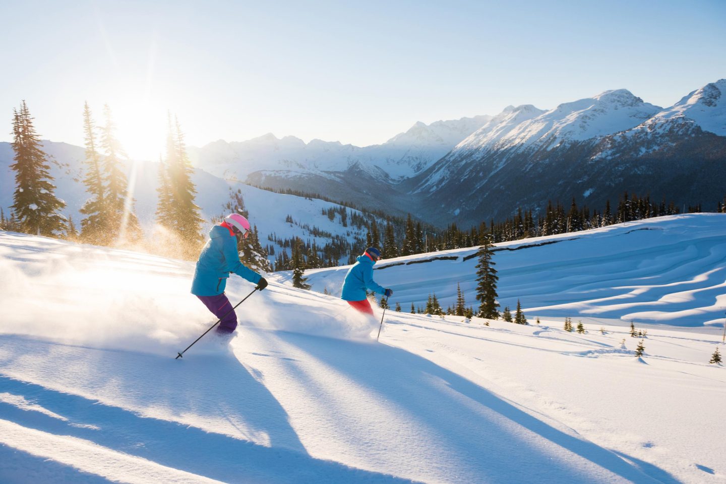 Skifahrer auf verschneiter Piste bei Sonnenaufgang in den Bergen.