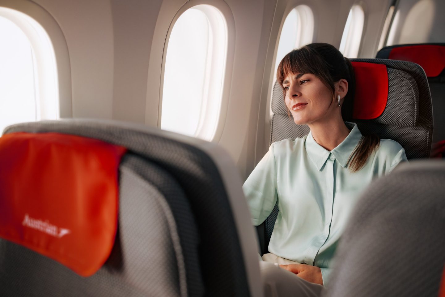 A woman sitting in an airplane seat looking out the window.