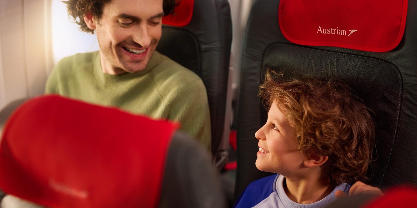 Ein lächelnder Vater und sein Sohn genießen ihren Flug mit Austrian Airlines.