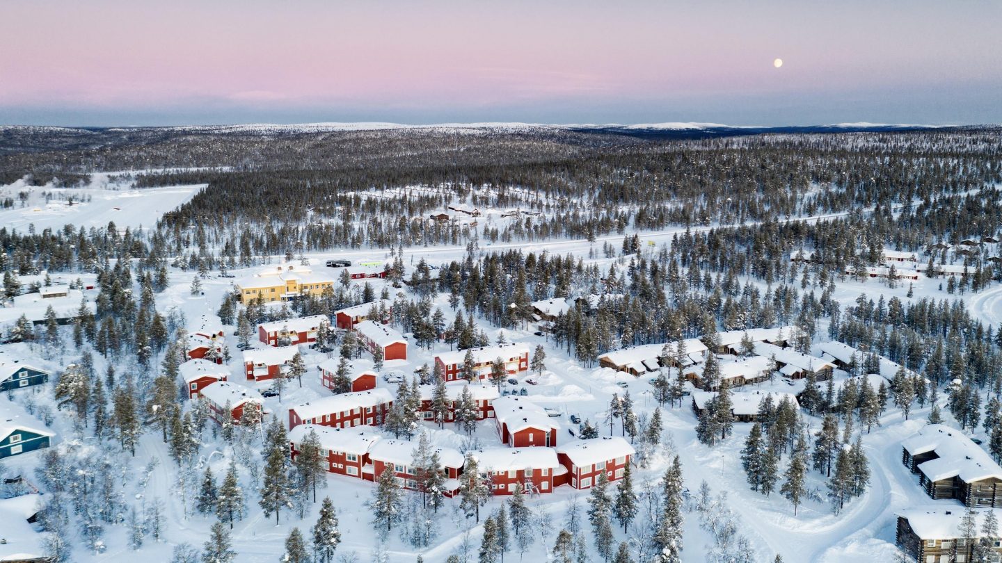 Arctic sunrise over the snowy forest and traditional huts of Saariselka tourist resort, Inari, Lapland, Finland