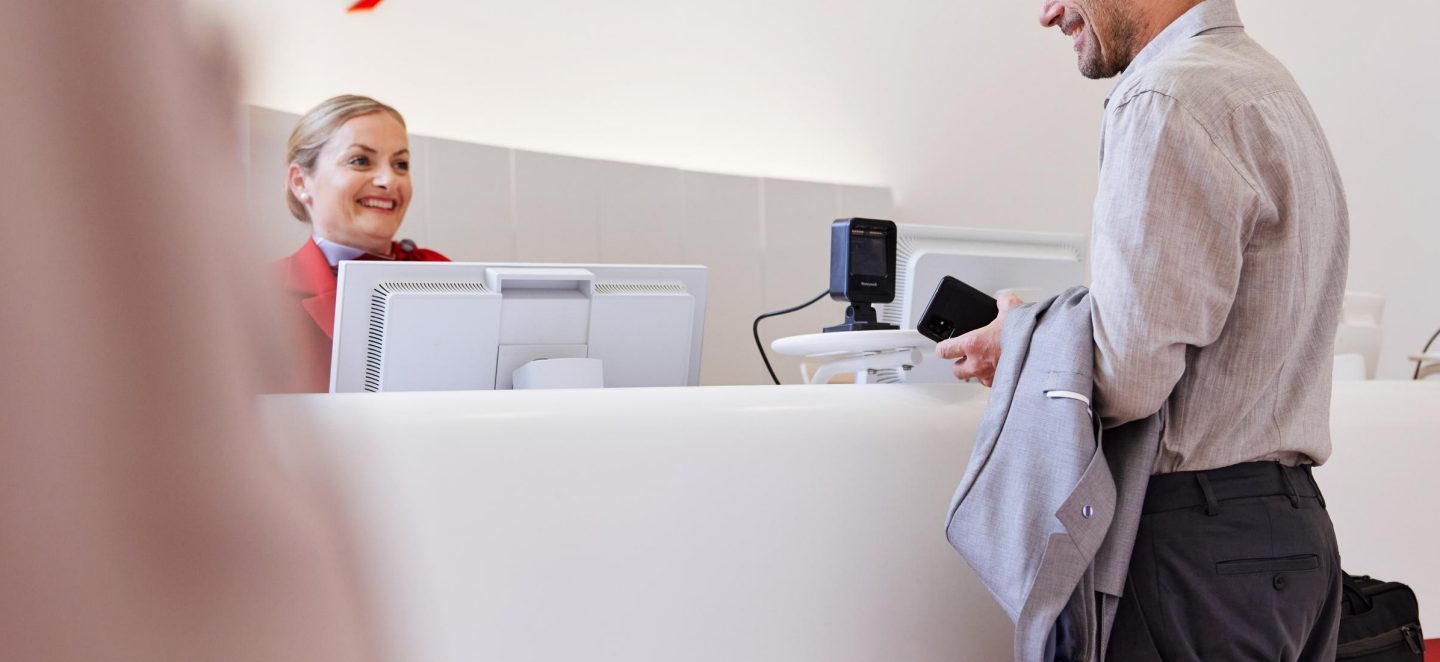 A friendly lounge receptionist assisting a passenger at the service counter.
