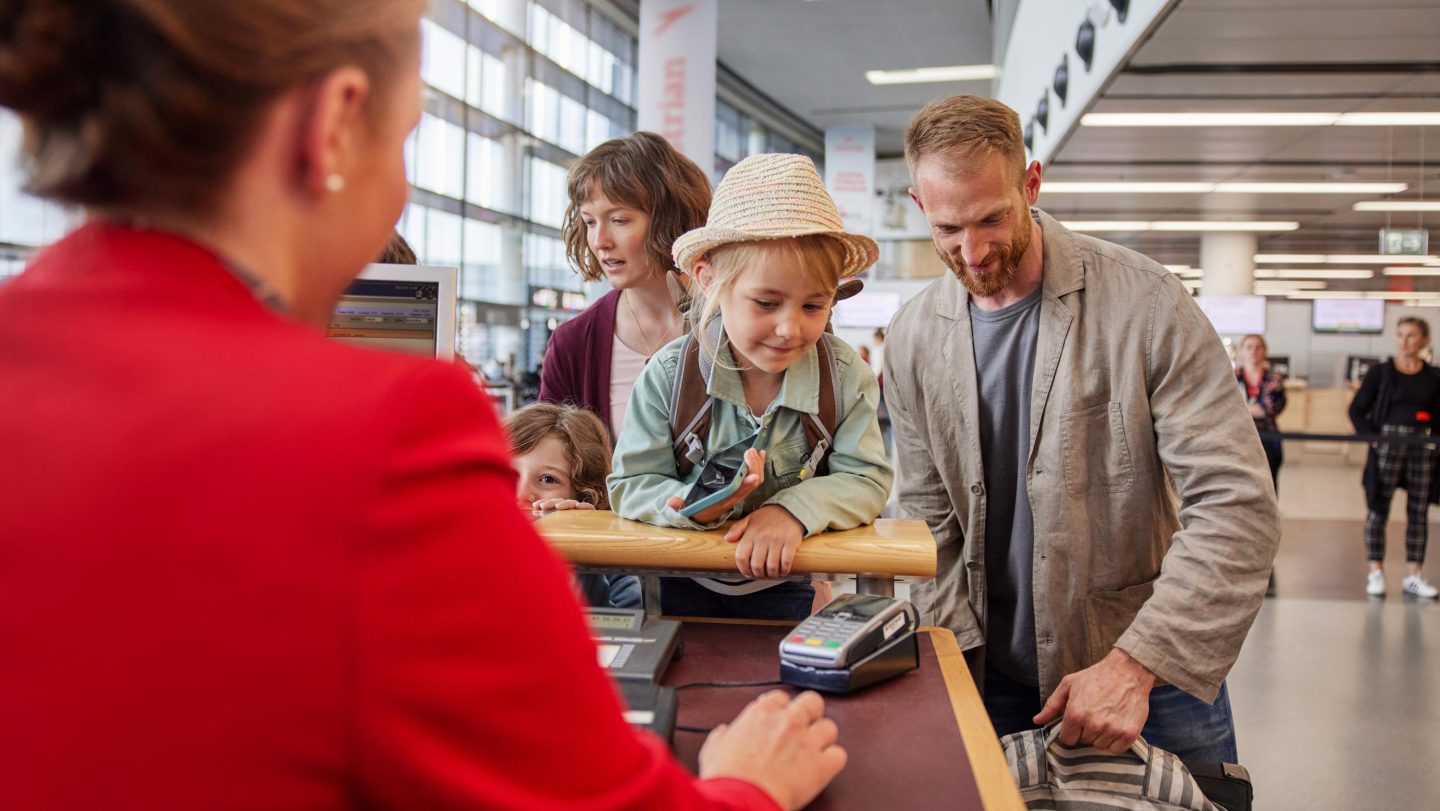 Eine Familie am Check-in-Schalter bei der Reisevorbereitung.