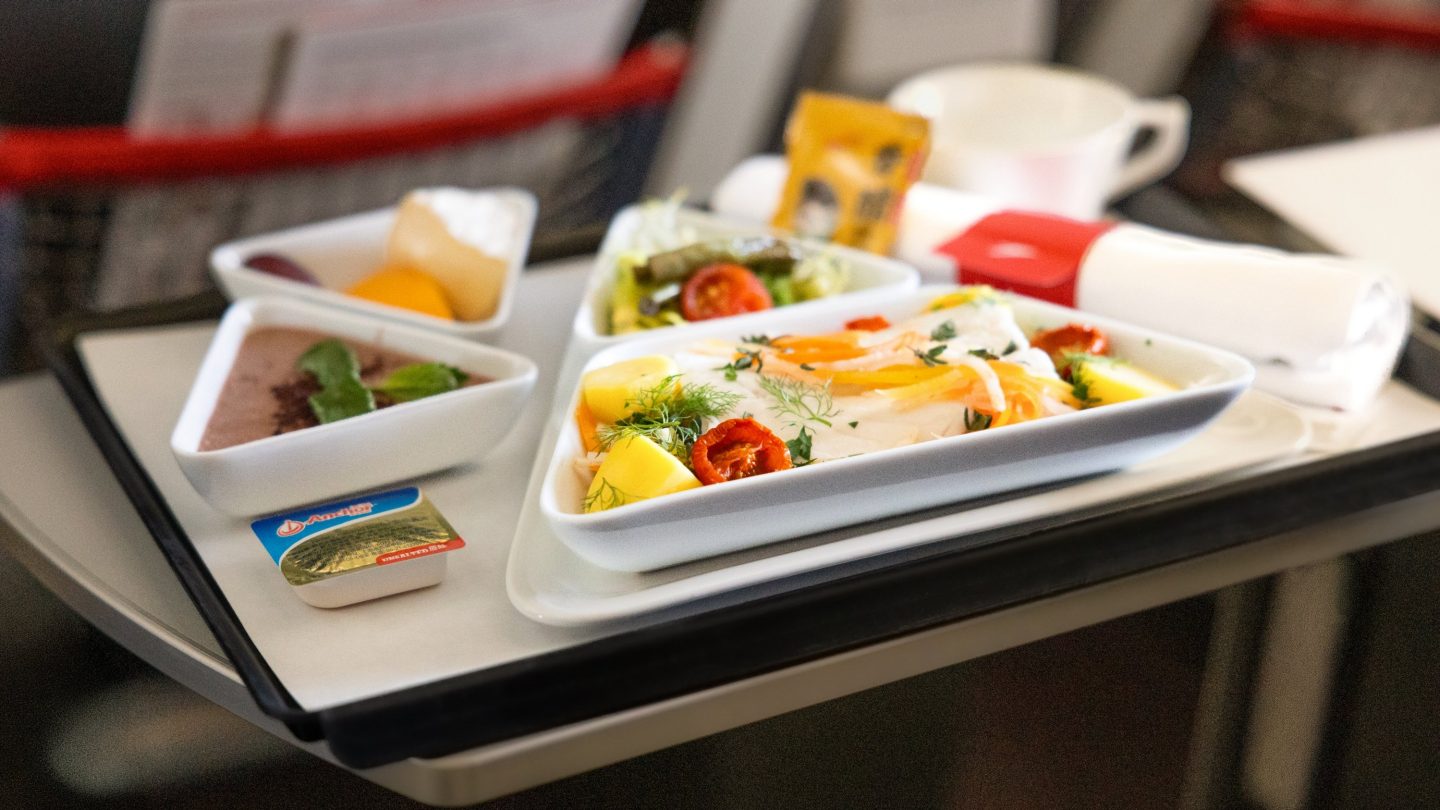 A special meal served on an airplane tray, featuring fresh vegetables, fish, and dessert.