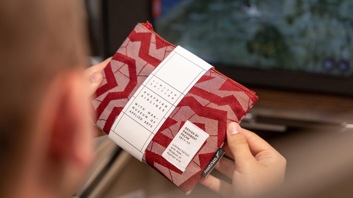 A man with short hair holding a red and white paper bag.