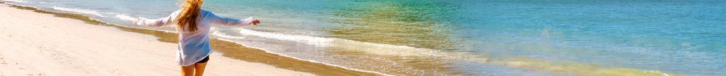 Frau am sonnigen Strand in Bangkok mit türkisblauem Meer und hellem Sand.