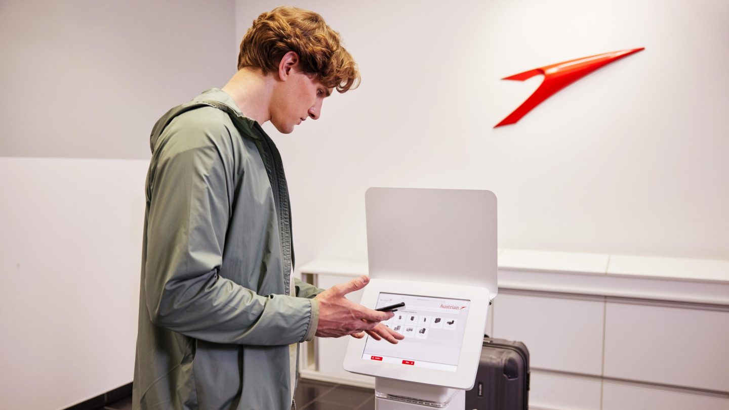 A young man uses a self-service check-in kiosk at the airport.
