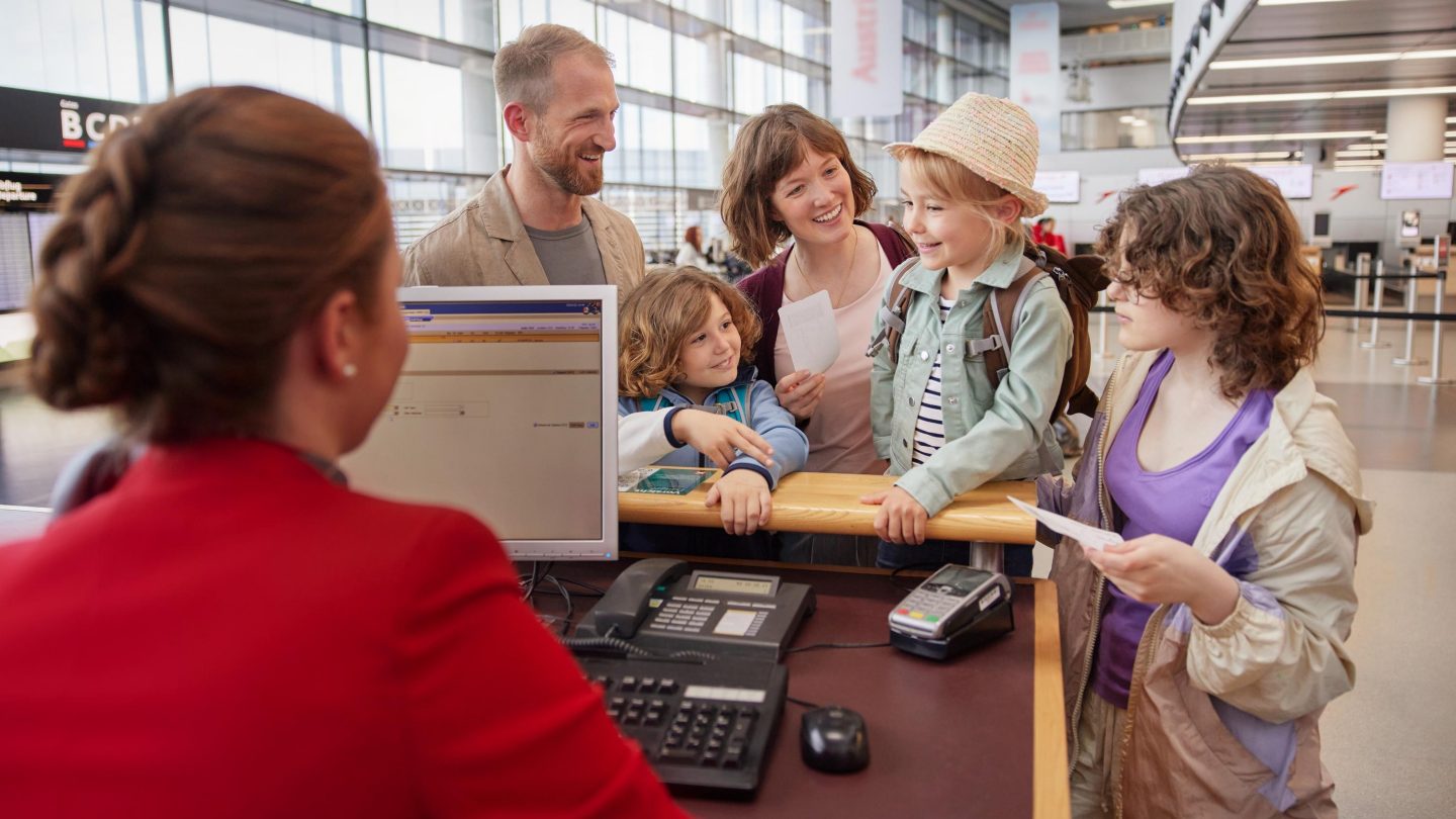 Eine Familie beim Check-in am Flughafen-Schalter.