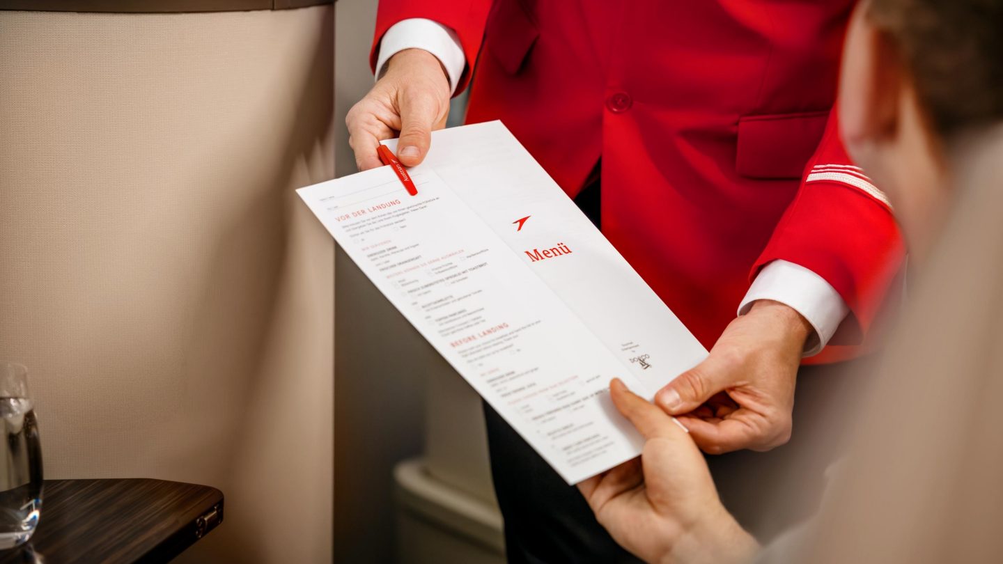 A man dressed in a red suit is examining a menu in his hands.