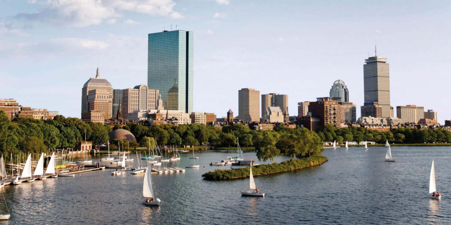 Boston skyline with sailboats on the water, showcasing a vibrant cityscape and recreational boating activity.