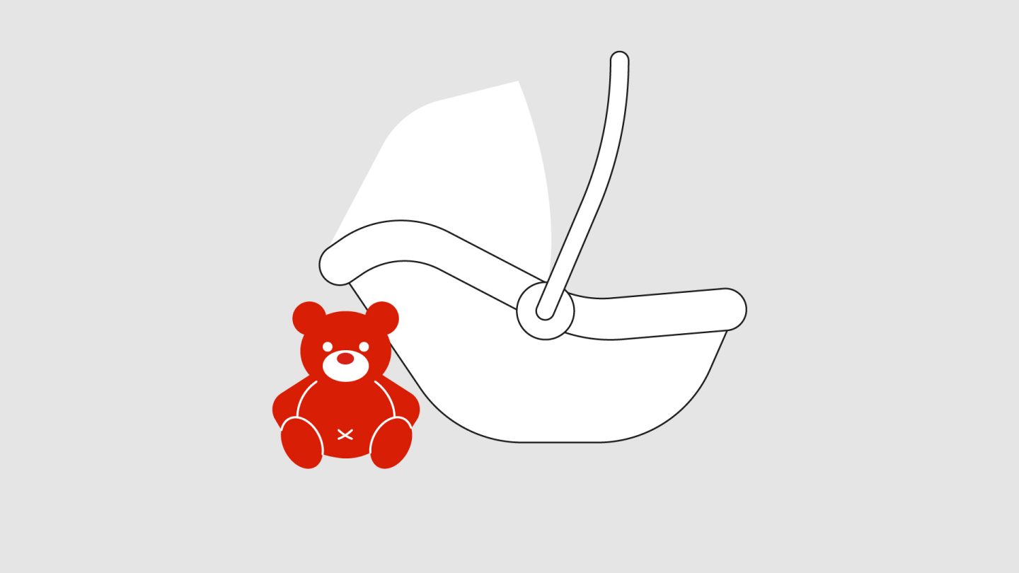 Red teddy bear beside a black-and-white baby car seat.