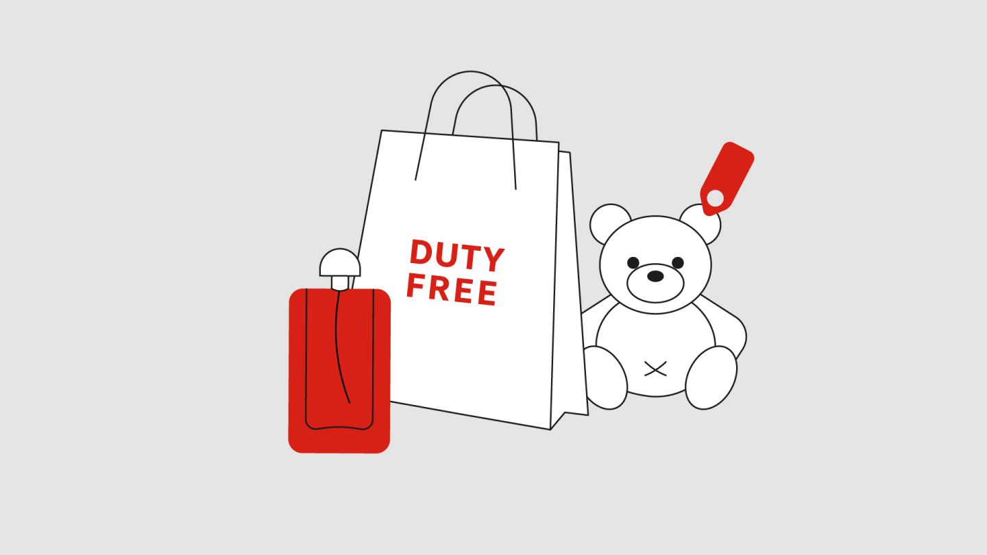 Duty-free bag beside a red bottle and a teddy bear with a sale tag.