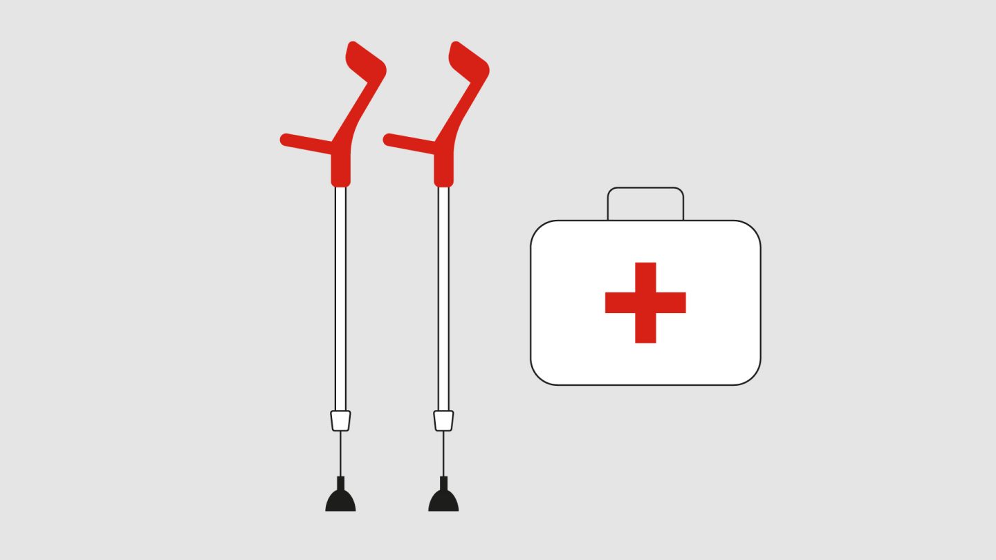 Crutches with red handles next to a white first aid kit.