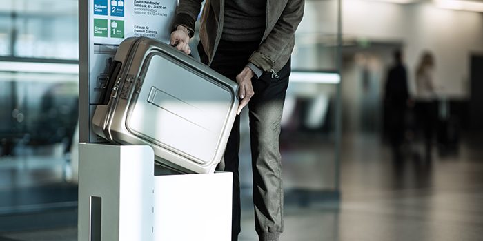 A man checks the size of his hand luggage at the airport
