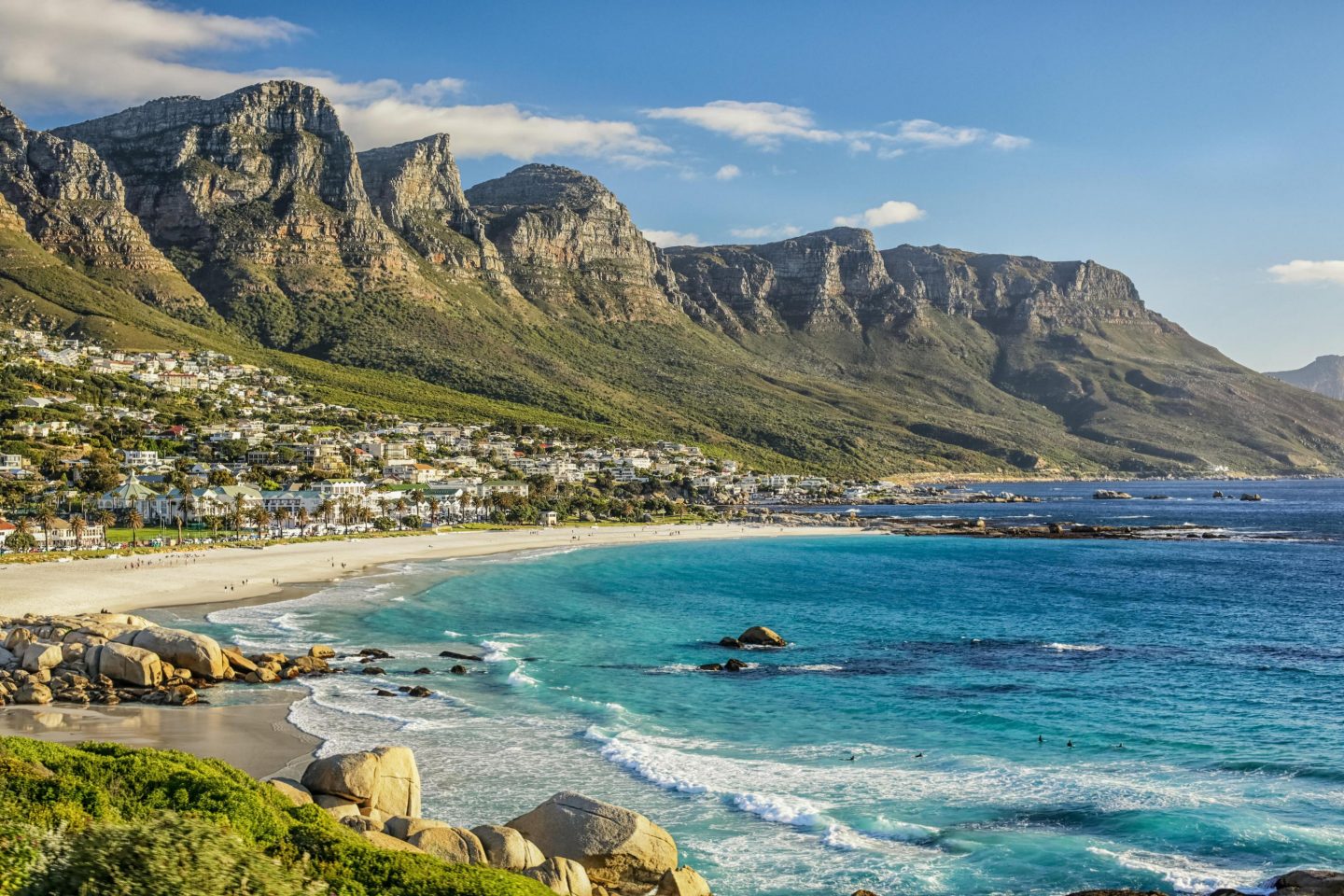 Panoramic view of a tropical beach with turquoise water and mountains.